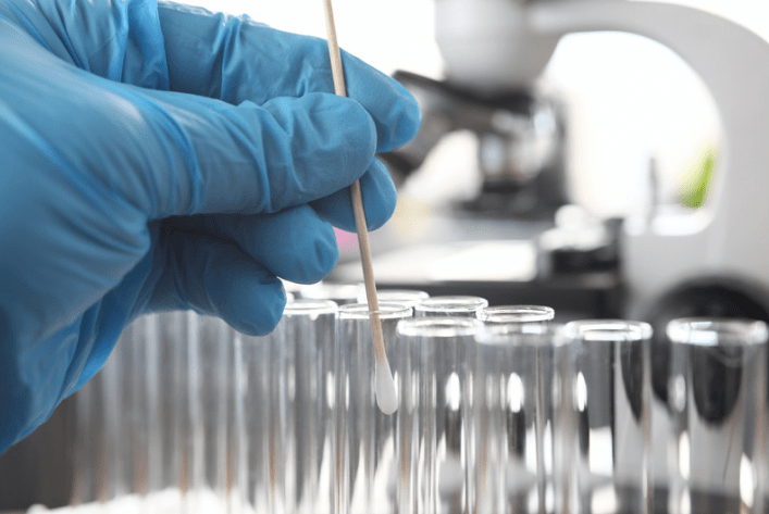 A cotton swab being inserted into a sample tube to prepare for DNA extraction 